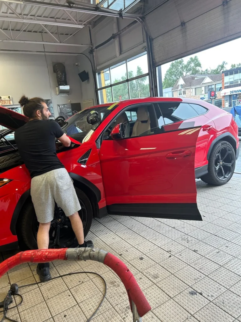Maintenance de pare-brise sur une voiture rouge chez Vite Vitres Jacques à Montréal.